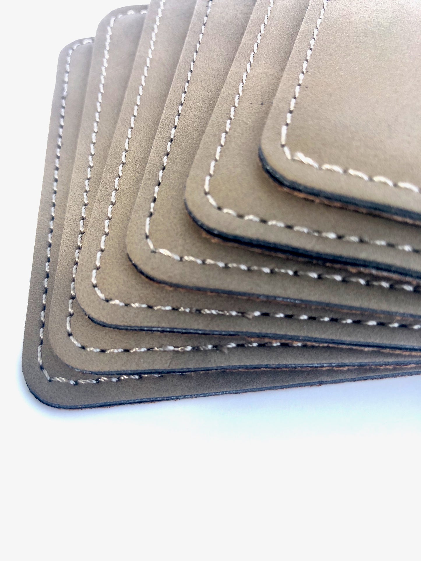 Close up view of 6 Buckskin coasters and quality stitching.