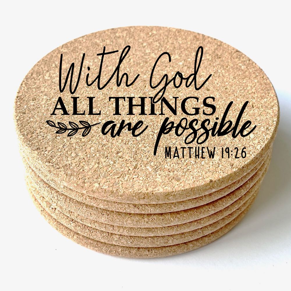 Close up view of a stack of 6 round cork coasters. The top coaster is engraved with the Bible verse: "With God all things are possible Matthew 19:26".