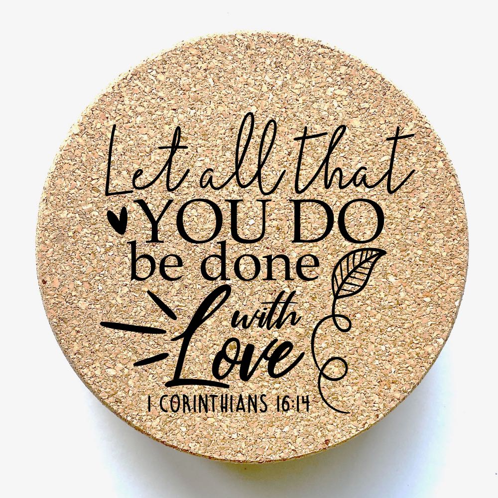 Close up view of one of the 6 round cork coasters with the Bible verse: "Let all that you do be done with love - I Corinthians 16:14".