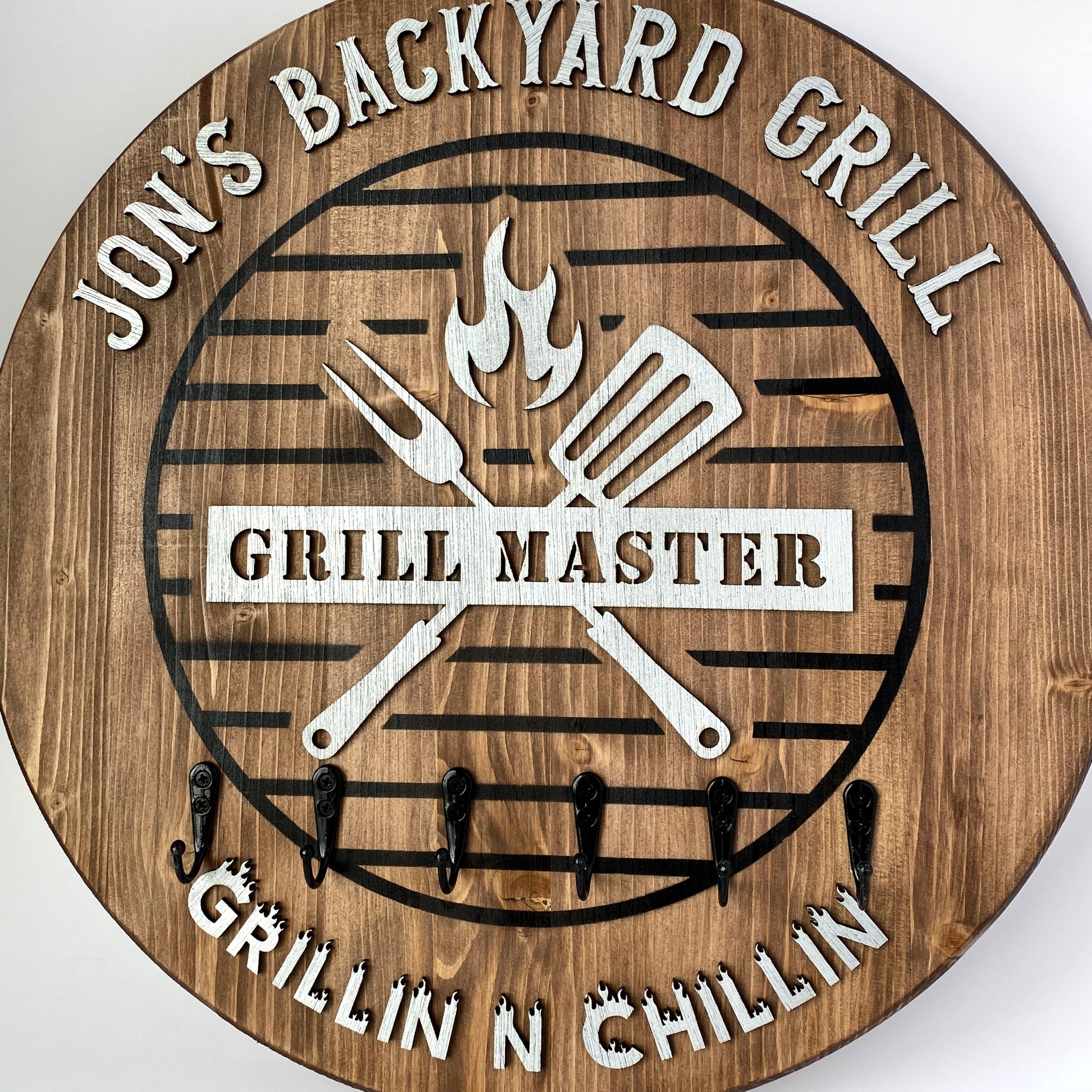 Vintage rustic oak wooden 18 inch round BBQ sign with 6 hooks for holding cooking utensils. Personalized with metallic silver lettering.