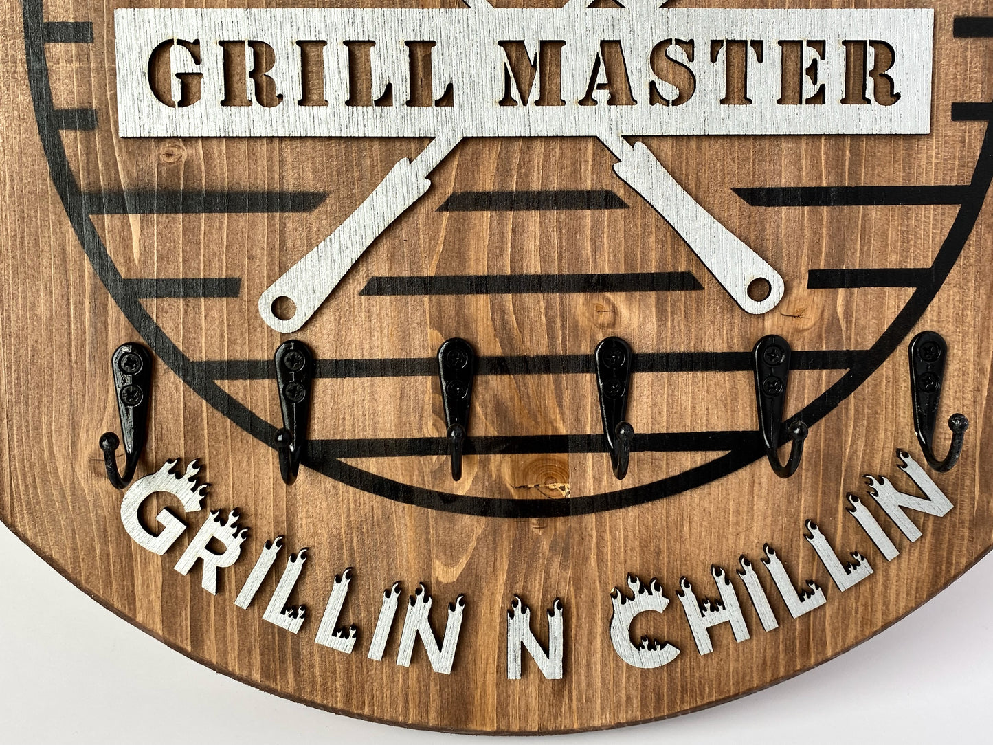 Wooden 18 inch round BBQ sign with 6 metal hooks for hanging utensils. Comes in Rustic Oak or Classic Grey. 