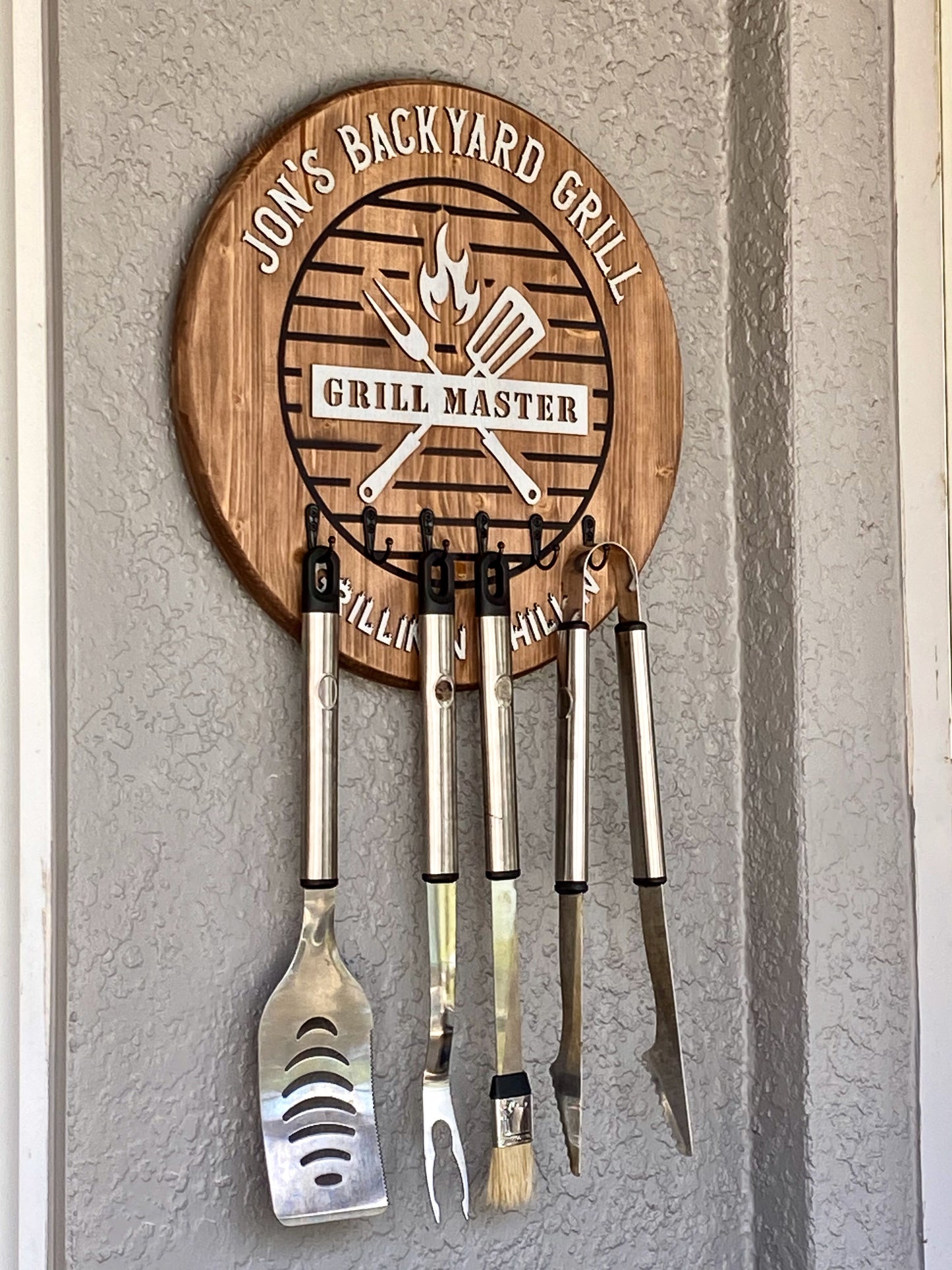 Vintage rustic oak wooden 18 inch round BBQ sign with 6 hooks for holding cooking utensils.  Sign hung on an outside wall to show it's practical use. (Utensils not included)