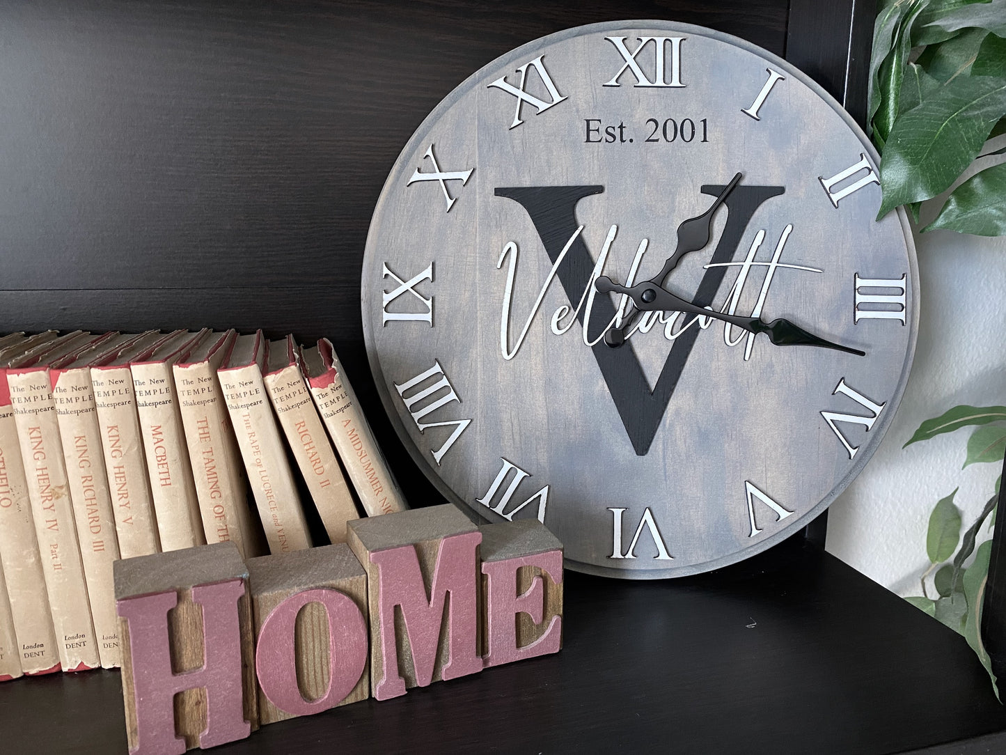 Vintage wooden 12 inch round custom Monogram name clock with surname and initial and wedding or special date. Displayed on a shelf as home decor.